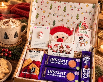 May include: A Christmas gift box containing two Cadbury Instant Hot Chocolate packets, a Cadbury Dairy Milk Little Bar, a Walkers Shortbread Fingers 40g pack, a crocheted Santa face, and two cards featuring a snowman and three gnomes.