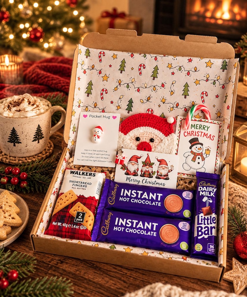 May include: A Christmas gift box containing two Cadbury Instant Hot Chocolate packets, a Cadbury Dairy Milk Little Bar, a Walkers Shortbread Fingers 40g pack, a crocheted Santa face, and two cards featuring a snowman and three gnomes.