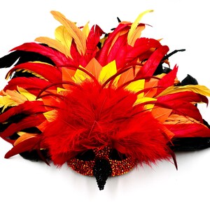 May include: A vibrant, feathered mask in shades of red, orange, yellow, and black. The mask features a beaded base and a central cluster of red feathers, creating a dramatic and eye-catching design. Ideal for costume parties or theatrical performances.