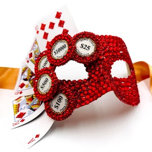 Peut inclure: Un masque de bal rouge incrusté de bijoux avec des jetons de poker et des cartes à jouer. Le masque présente des jetons de poker avec des valeurs de 25, 100, 500 et 10 000. Des cartes à jouer, dont un As et un 10, sont visibles.