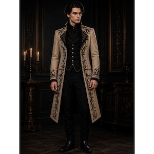 May include: A tan long coat featuring black floral embroidery along the lapels and hem, worn over a black button-up waistcoat with a silver chain detail and black trousers. The coat has a high collar and long sleeves with black cuffs, creating a structured silhouette.