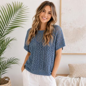 May include: A short-sleeved blue knit top featuring an intricate openwork chevron pattern, a round neckline, and a ribbed hem. The garment is constructed with a lightweight, breathable yarn, showcasing a textured, semi-sheer design throughout the body.