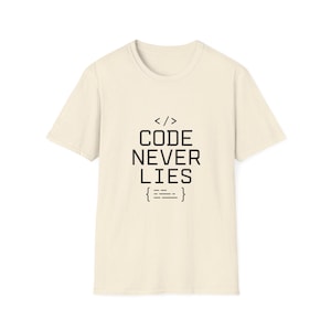 Peut inclure: Un t-shirt à manches courtes de couleur crème avec une impression graphique noire sur la poitrine. Le motif comprend le texte CODE NEVER LIES, placé entre un symbole de crochet de code en haut et un élément de ligne entre crochets en bas.