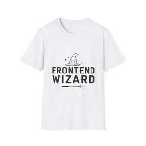 Op de afbeelding: Een wit t-shirt met korte mouwen en een zwarte grafische print. Het ontwerp bevat een tovenaarshoed met code-haakjes, de tekst FRONTEND WIZARD en een toverstaf-icoon met kleine steraccenten onder de tekst.