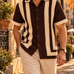 Peut inclure: Une chemise à manches courtes en crochet avec une base marron foncé et des rayures verticales couleur crème. La chemise présente un col, une fermeture boutonnée sur le devant avec cinq boutons foncés, et des bords crème aux manches.