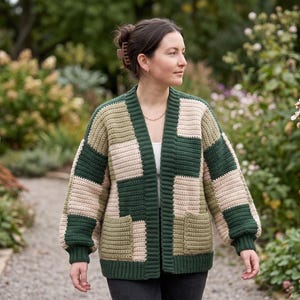 May include: A crochet cardigan featuring a patchwork design in shades of dark green, olive green, and beige. The garment has long sleeves with ribbed cuffs, a ribbed hem, and two front pockets. The construction consists of rectangular panels.