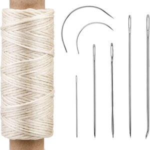 May include: A spool of off-white thread with a brown cardboard core, accompanied by a set of sewing needles including two curved needles and four straight needles of varying lengths, all made of polished silver-colored metal.
