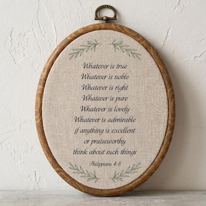 Peut inclure: Un cadre ovale de tambour à broder en bois foncé contenant un tissu beige. Le tissu présente un texte imprimé en noir : Whatever is true, Whatever is noble, Whatever is right, Whatever is pure, Whatever is lovely, Whatever is admirable, if anything is excellent or praiseworthy, think about such things, Philippians 4:8, avec des illustrations de feuilles vertes en haut et en bas.