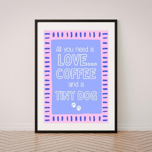 May include: A framed wall art print featuring a light blue rectangular centre with the white text All you need is LOVE... COFFEE and a TINY DOG, accented by two small white paw prints, surrounded by a pink border with blue dash marks.
