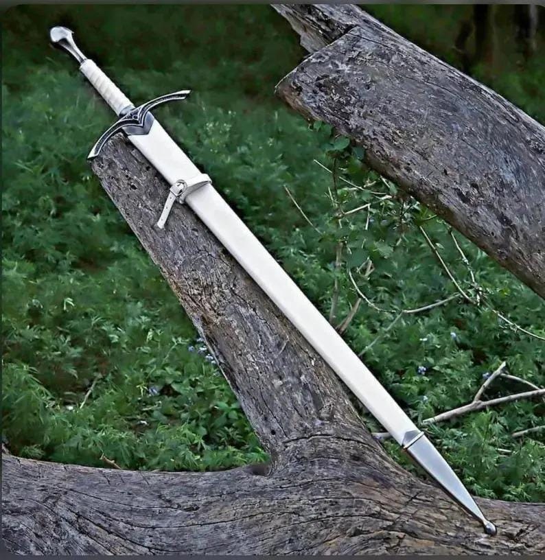 May include: A long sword with a white scabbard and a silver-toned hilt. The hilt features a cross-guard with intricate metal detailing and a white grip. A small white strap is attached to the scabbard, which ends in a pointed silver-toned metal tip.