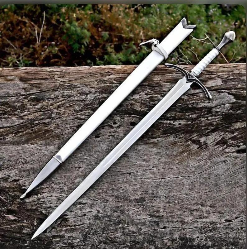 May include: A silver-toned sword with a white handle and a matching white scabbard. The sword features a pointed blade, a crossguard with dark detailing, and a rounded pommel. The scabbard includes a white strap and a silver-toned metal tip.