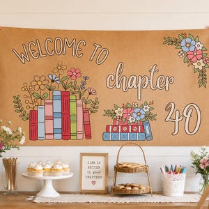 May include: A rectangular tan fabric banner featuring the text "WELCOME TO chapter 40" in a dark brown font. The design includes colorful illustrations of stacked books with flowers emerging from the top and a floral bouquet in the corner.