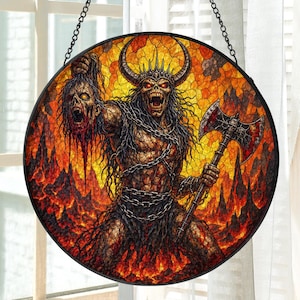 Può includere: Un acchiappasole circolare in vetro colorato raffigurante una figura demoniaca cornuta con occhi rossi luminosi, che tiene una testa mozzata in una mano e una grande ascia da battaglia nell'altra, su uno sfondo arancione e giallo con catene nere.
