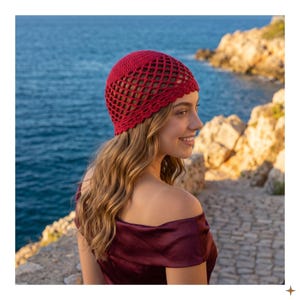 May include: A vibrant red crochet beanie featuring a solid circular crown and a wide, open-work diamond lattice pattern throughout the body. The lower edge is finished with a delicate, scalloped crochet border that frames the head.