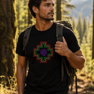 May include: A black short-sleeved t-shirt featuring a centred graphic design of a purple spiral enclosed within a multi-layered, stepped geometric cross pattern outlined in red, yellow, green, and blue lines, worn with a dark backpack.