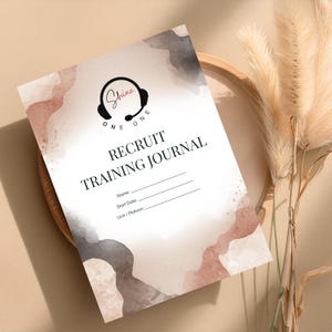 May include: A rectangular recruit training journal with a white background featuring abstract watercolor shapes in shades of dusty rose and charcoal gray. The cover displays a black headset icon with the text Shine One One, Recruit Training Journal.
