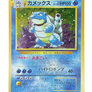 Peut inclure: Une carte à collectionner holographique japonaise Blastoise présentant le personnage dans des tons bleu et beige. La carte affiche le nom Kamex, HP100 et des symboles de type eau. Le texte inclut la capacité spéciale Rain Dance et Hydro Pump.