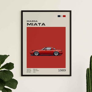 Peut inclure: Une affiche encadrée présentant une illustration de Mazda Miata rouge sur fond rouge. Le texte inclut MAZDA MIATA, 1989, et des spécifications techniques : 133 HP, 160 NM, 8.5 SEC, 950 KG, 190 KM/H, 1.6 L. Un petit drapeau français est en haut à droite.