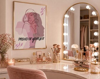 May include: A rectangular wall art print in a gold frame featuring a line art illustration of a person holding a rose, with pink and purple abstract shapes in the background and the black text PROUD OF YOURSELF printed on the lower portion.