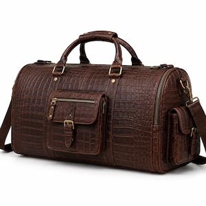 May include: A dark brown duffel bag with a textured crocodile skin pattern. The bag features two top handles, a detachable shoulder strap, a large front pocket with a zip and buckle closure, and a side pocket, all accented with brass hardware.