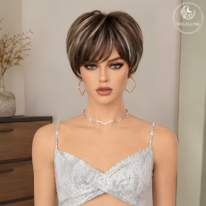 May include: A short, layered brown wig with blonde highlights and side-swept bangs. The wig features a textured, voluminous cut with darker roots and lighter streaks throughout. The WIGELUNE logo is visible in the top right corner of the image.