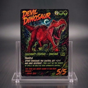 May include: A rectangular trading card titled Devil Dinosaur featuring a red dinosaur illustration, set in a clear acrylic display stand. The card text includes Legendary Creature - Dinosaur, Trample, and power/toughness stats of 5/5.