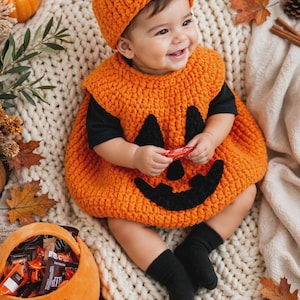 Peut inclure: Un costume de citrouille en crochet composé d'une tunique orange vif sans manches avec un visage de jack-o'-lantern noir et un bonnet orange assorti avec une tige verte. La tenue est portée sur un t-shirt noir et des chaussettes noires.