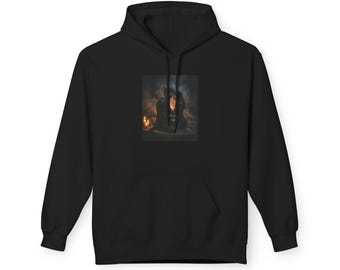 May include: A black hooded sweatshirt featuring a rectangular graphic print on the chest. The print depicts two figures sitting together in a dimly lit, atmospheric space illuminated by warm, glowing candles, creating a soft, hazy visual effect.