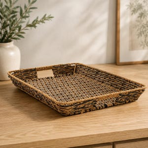 May include: A rectangular woven tray featuring a blend of natural light brown and dark brown fibers. The tray has a low profile with a flat base and integrated handles on two sides, constructed with a tight, crisscross weave pattern throughout.