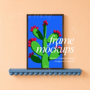 May include: A rectangular dark brown frame containing a print of a green prickly pear cactus with red fruit against a solid blue background. The frame rests on a blue shelf with a decorative row of spheres along the bottom edge.