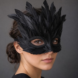 May include: A black masquerade mask adorned with layered black feathers extending upwards and outwards. The eye openings are framed with a decorative black braided trim, and the mask is secured with a simple black elastic strap around the head.
