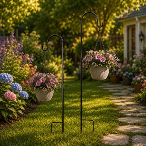 May include: Two black metal shepherd hooks of varying heights, each featuring a curved top and a pronged base. Suspended from each hook is a light-colored, ribbed hanging planter filled with a vibrant arrangement of pink and purple flowers.