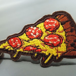 Puede incluir: Parche bordado para planchar en forma de porción de pizza con pepperoni rojo y una corteza amarilla.