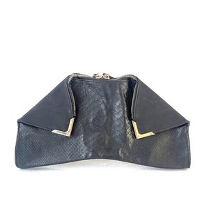 May include: Black clutch purse with a snakeskin pattern and gold zipper pulls. The purse has a unique, angular shape.