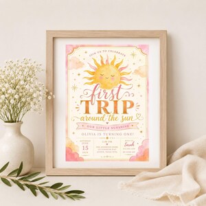May include: A framed birthday invitation featuring a watercolor illustration of a smiling sun with pink and yellow clouds. The text reads: JOIN US TO CELEBRATE FIRST TRIP AROUND THE SUN OUR LITTLE SUNSHINE OLIVIA IS TURNING ONE SATURDAY JUNE 15 2024.
