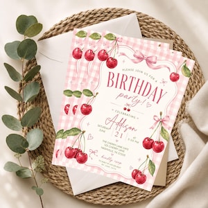 Op de afbeelding: Een rechthoekige uitnodigingskaart voor een verjaardagsfeest met een roze-witte gingham achtergrond, geïllustreerd met aquarel kersen, roze linten en strikken. De tekst luidt: Please join us for a birthday party! Celebrating Addison, Saturday June 21 at 5:00 PM, The Cherry Lane Cafe, 123 Cherry Lane, Nashville, TN 37205. Kindly RSVP to Emily at 675.123.4567 by June 14th.