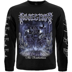 May include: A black long-sleeve t-shirt featuring a graphic of a horse-drawn carriage in a graveyard. The text DISSECTION appears at the top, and The Somberlain is printed below the carriage. The sleeves feature repeating white logo text.
