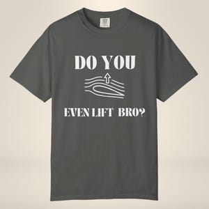 May include: A charcoal gray short-sleeve t-shirt featuring white text that reads DO YOU EVEN LIFT BRO? with a central graphic of an airfoil shape and curved lines indicating airflow with an upward arrow representing aerodynamic lift.