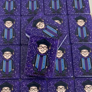 Puede incluir: Una colección de latas rectangulares con purpurina morada, cada una con una ilustración de dibujos animados de un graduado con toga y gafas. El texto en la toga dice "CONGRATS" y "CLASS OF 2025". Las latas están dispuestas en un patrón de cuadrícula.