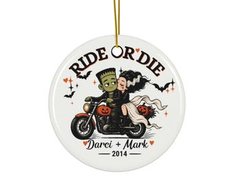 Puede incluir: Un adorno redondo de cerámica blanca con una ilustración de dibujos animados de Frankenstein y su novia en una motocicleta. El texto RIDE OR DIE está impreso arriba, con Darci + Mark y 2014 abajo. El diseño incluye murciélagos, estrellas y calabazas.
