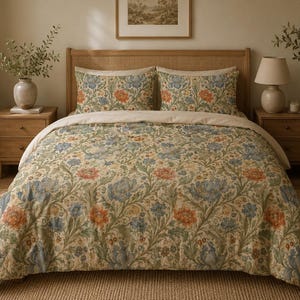 May include: A bedding set featuring a duvet cover and two matching pillowcases with a cream background and a dense botanical pattern of blue and orange flowers with green foliage. The fabric displays a repeating floral motif across the entire surface.