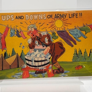 May include: A vintage postcard titled THE UPS AND DOWNS OF ARMY LIFE !! featuring a cartoon soldier washing clothes in a wooden tub on a red stool. A clothesline with various garments hangs above, with tents and a yellow sun in the background.