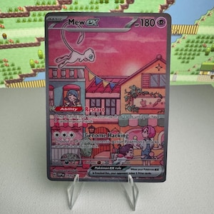 May include: A Mew ex trading card featuring a pink-toned illustration of the character flying above a town scene with buildings, bunting, and people. The card displays 180 HP, the Ability Restart, the attack Genome Hacking, and Pokémon ex rule text.