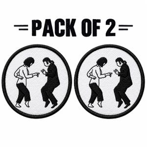 May include: A pack of two circular embroidered patches featuring a black and white graphic of two figures dancing. The text PACK OF 2 is printed in black above the patches. Each patch shows a person in a light shirt and dark trousers dancing.