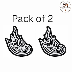 May include: A pack of two embroidered patches featuring a black and white design of a stylized eye surrounded by flame-like patterns. The patches have a thick black border and intricate white stitching details, presented with the text Pack of 2.