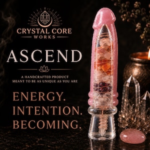 May include: A phallic-shaped object made of pink translucent material with a clear glass core filled with various small, multi-coloured stones wrapped in copper wire. The text reads CRYSTAL CORE WORKS, ASCEND, A HANDCRAFTED PRODUCT MEANT TO BE AS UNIQUE AS YOU ARE, ENERGY. INTENTION. BECOMING.