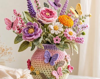 Può includere: Una composizione floreale all'uncinetto in un vaso rotondo dai colori sfumati. Il bouquet presenta fiori all'uncinetto rosa, viola, gialli e bianchi, foglie verdi e diverse piccole farfalle all'uncinetto attaccate ai gambi e al vaso.