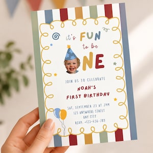 Puede incluir: Una tarjeta de invitación para el primer cumpleaños con un borde de rayas verticales en azul, rojo y amarillo. El texto dice it's FUN to be ONE, JOIN US TO CELEBRATE NOAH'S FIRST BIRTHDAY, con detalles del evento y la foto de un niño.