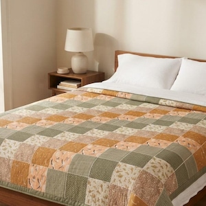 May include: A patchwork quilt featuring a repeating grid of square fabric panels in alternating shades of sage green, mustard yellow, and cream. The quilt displays a variety of subtle patterns including small dots, botanical motifs, and textures.