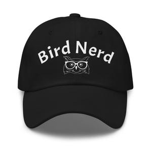 Może przedstawiać: Czarna czapka z daszkiem z białym napisem Bird Nerd wygiętym w łuk nad białą grafiką liniową przedstawiającą sowę w okularach. Czapka posiada usztywnianą koronę, zakrzywiony daszek oraz guzik na górze, co nadaje jej prosty i schludny wygląd.
